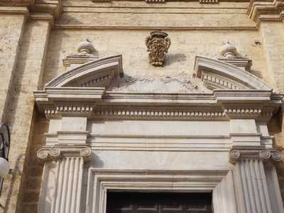 Il portale ligneo � inquadrato da pi� cornici rettangolari, affiancate da quattro paraste scanalate con capitelli ionici. Questi reggono un timpano ad arco spezzato su cui domina lo stemma lapideo delle Carmelitane, con tre stelle e una croce centrale 